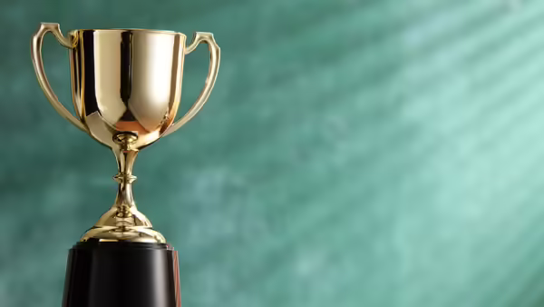A gold trophy in front of a teal background.