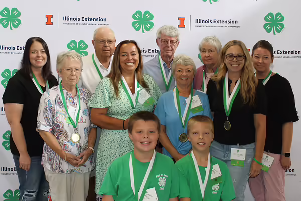 a smiling group standing in front of a 4-H backdrop
