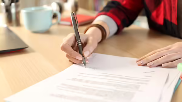 A person using a pen to write on paper. 
