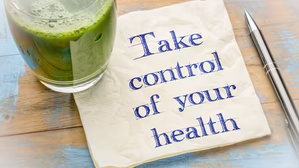 A napkin with the words, "Take control of your health" written on it, along with a class with a green smoothie in it.