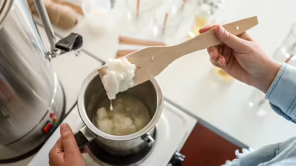 Melting down beef tallow in a metal pot and a wooden spoon.