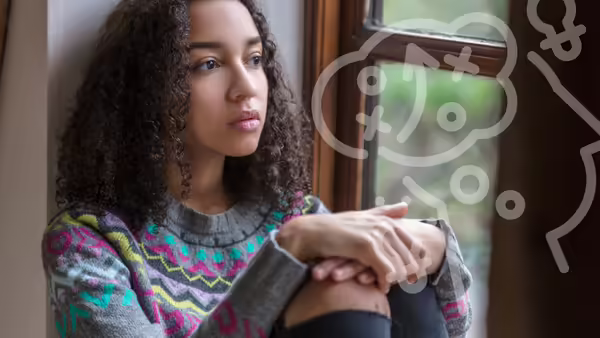 young lady sitting by a wall thinking 