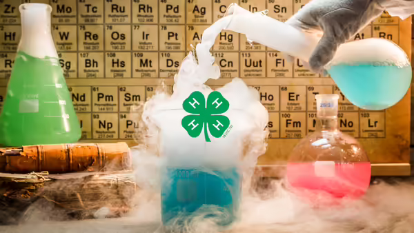 Laboratory beakers with colorful liquids and vapor in front of a periodic table, featuring a green 4-H emblem in the center.