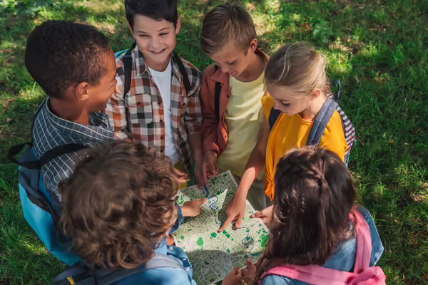 Kids standing in a circle looking at a map