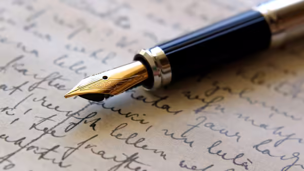 A fountain pen lies on an inscribed page.