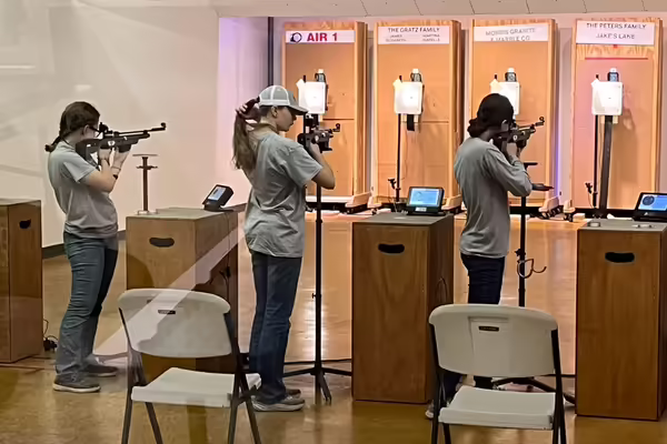three 4-H members aiming air rifles at targets
