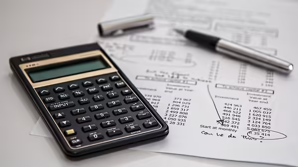 calculator, pen and financial sheet