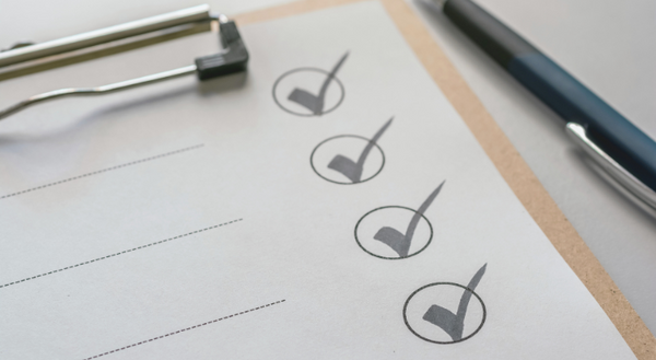 A blank checklist on a clipboard next to a pen.