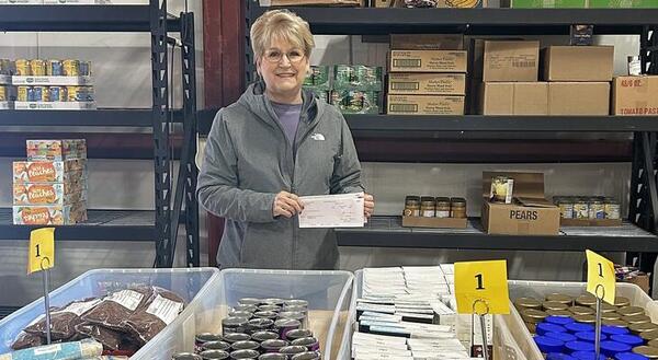 lady standing in front of a table full of food pantry donations
