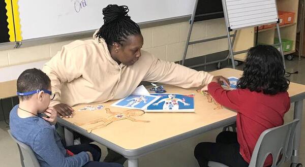 Teacher helps two students with project