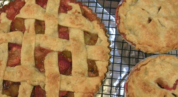 two small pies with full pastry tops and a large pie with a lattice work top cooling on a wire rack
