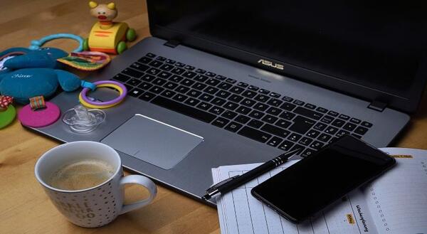 open laptop computer with a cup of coffee and baby toys