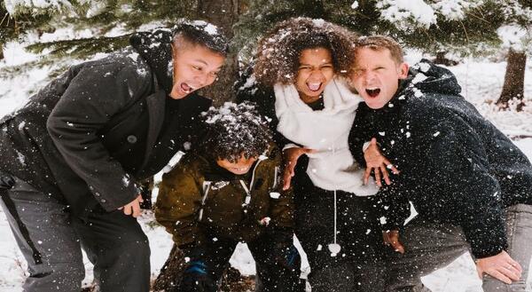 four people outside laughing in the snow