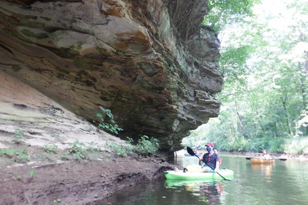 Woman in kayak close to rocky bluff