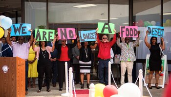 A group of people holding a sign that says: We are no longer a food desert