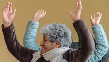 woman with grey hair head turned hands above head