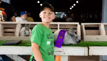 Michael Galloway poses in front of his rabbits and an award ribbon