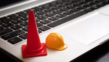 Traffic cone and hardhat on a laptop keyboard