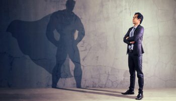 man in suit looking at shadow of superhero
