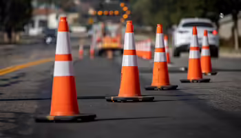 Traffic cones on road with electronic arrow pointing to the right to divert traffic and white car in distance
