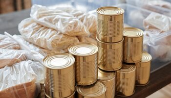 Canned goods, bred and noodles sitting on a table. 