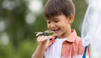 A boy with a dragonfly on his hand 