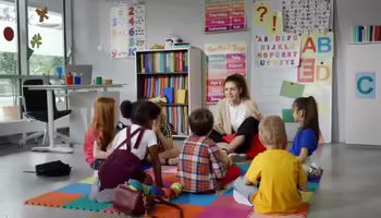 A teacher on the floor with her students 