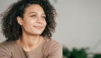 Woman staring off camera with closed lip smile