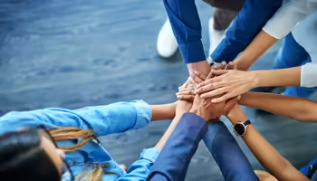 group of hands of various skin colors coming together in a sign of teamwork