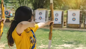 kids in archery shooting at paper targets