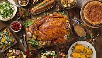 Thanksgiving table with turkey, pecan pie, sweet potatoes, salad, potatoes, cranberries