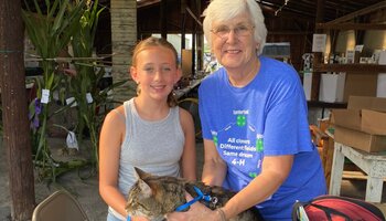 4-H Volunteer assisting a young 4-H member with her cat at the 4-H Fair.