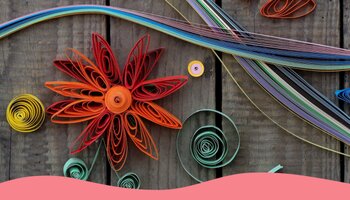 A quill paper flower and other designs on a wooden background.