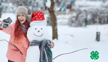 A smiling girl taking a selfie with a snowman. A green 4-H logo in the lower right corner.