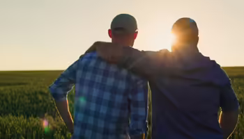 father and son farmers looking out over field