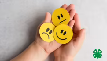 Hands holding paper with hand-drawn expressions: a sad face, a neutral face, and a happy face. A green 4-H clover logo is in the bottom right corner.
