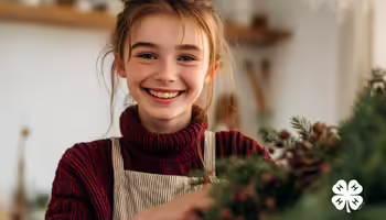 A girl holding holiday greenery. The white 4-H logo is in the bottom right corner.