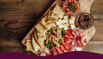 Wooden charcuterie board with meat, cheese, and bread.