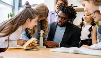 A Man Teaching Students How to Use a Microscope