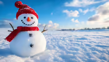A snowman with a red cap and scarf stand in a winter landscape. 