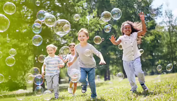 children running through bubbles at a park
