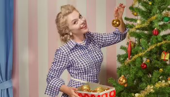 blonde woman putting ornaments on a tree