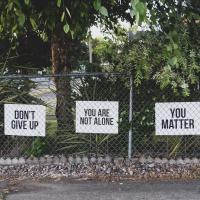 Signs on fence saying Don't Give Up, You are not Alone, and You Matter. 