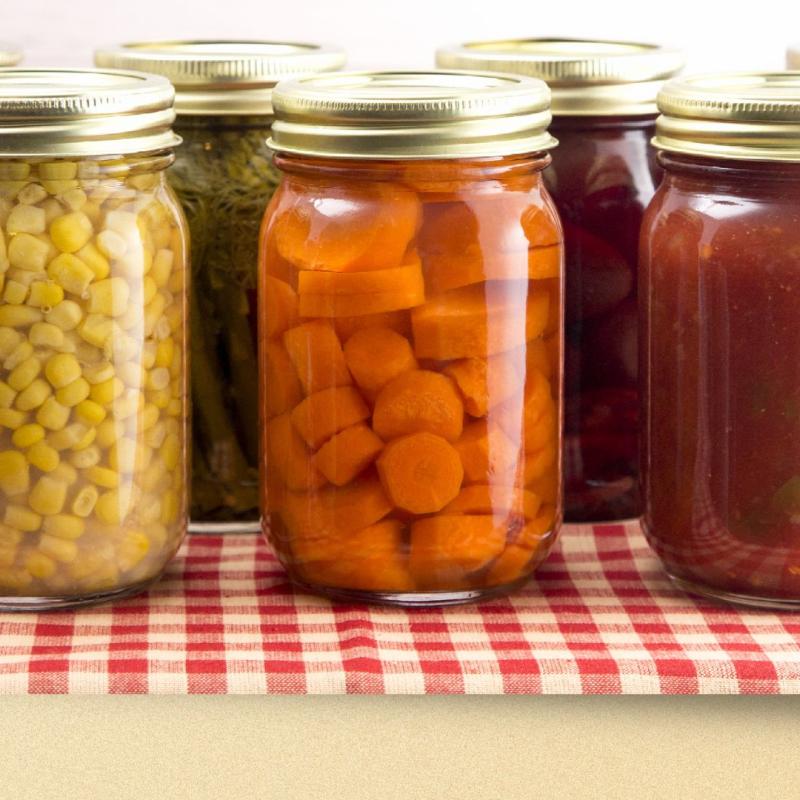 Corn, carrots and sauce in glass jars