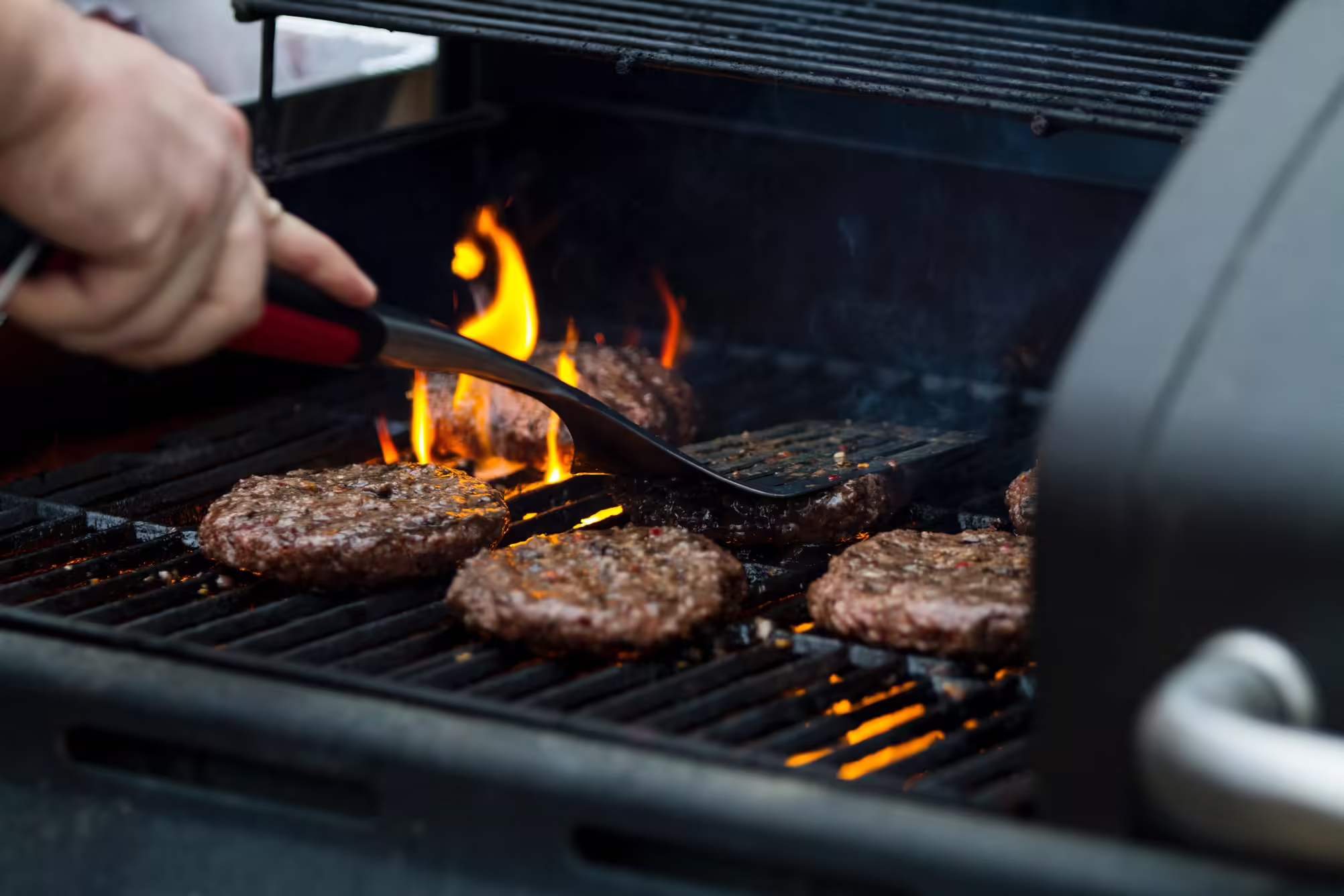 Person grilling beef patties
