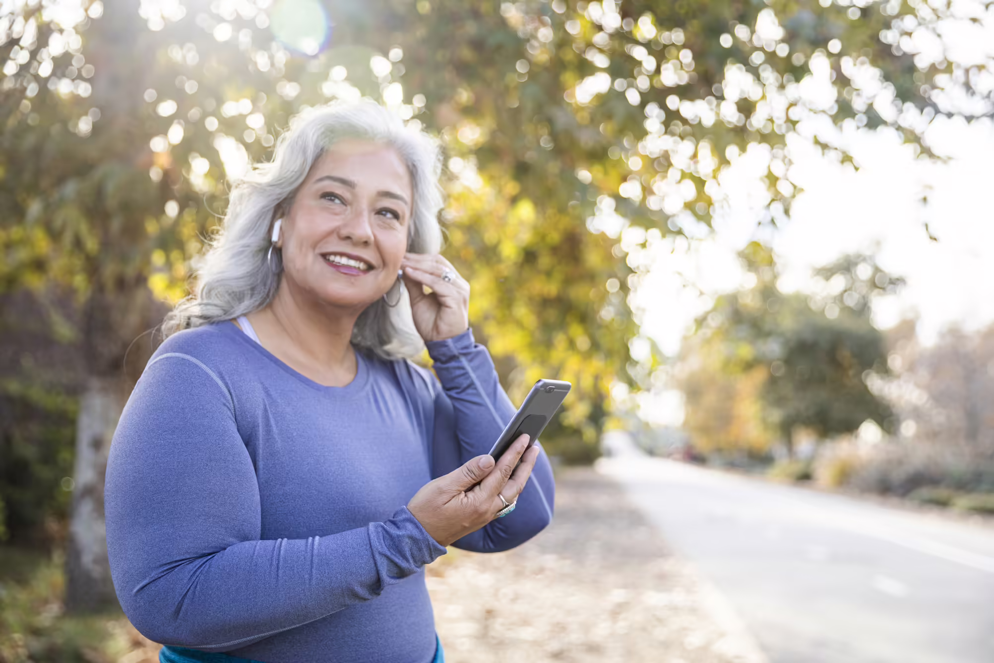 Woman exercising outdoors listening to podcast on her phone