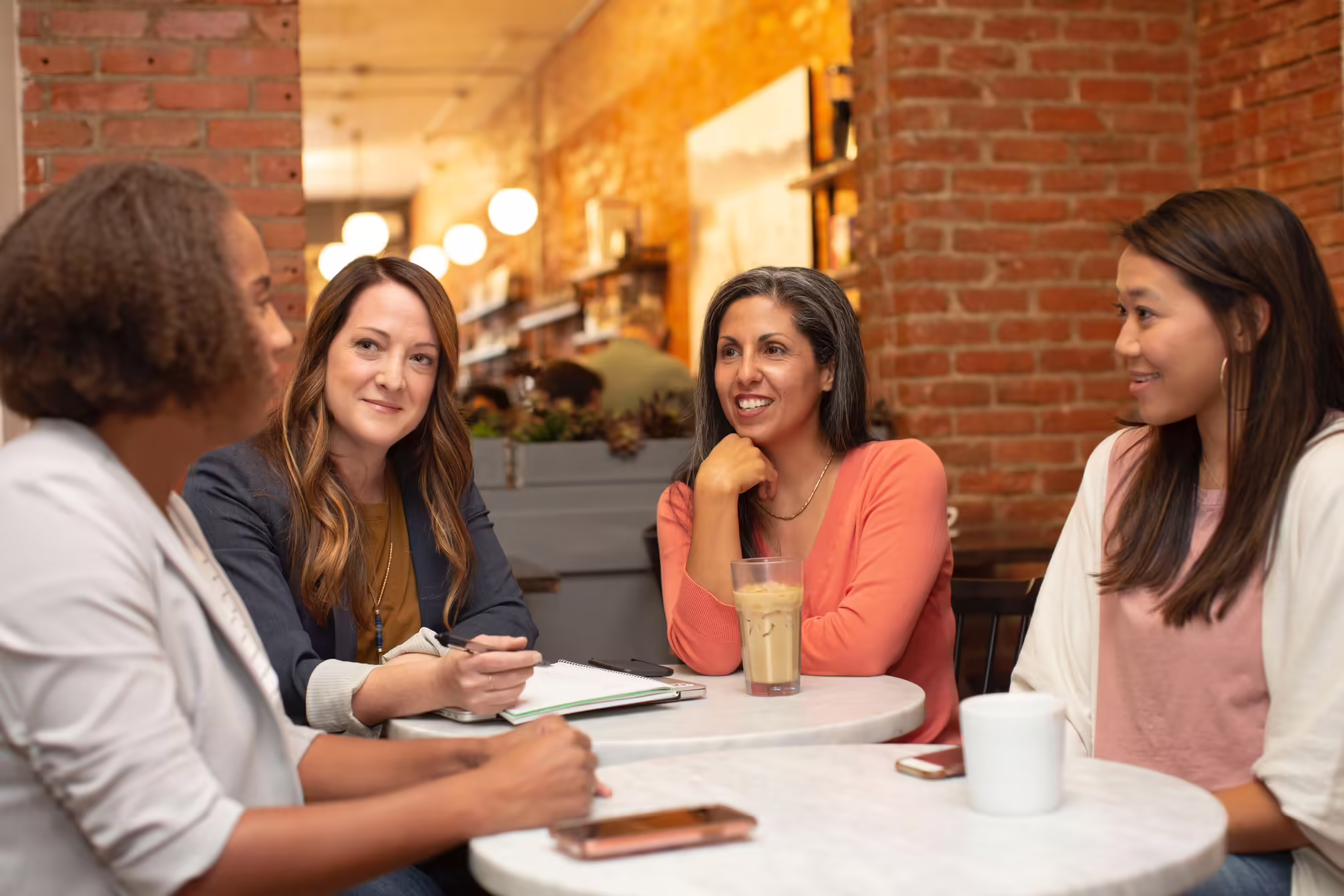 A group of women sitting around at a table talking.