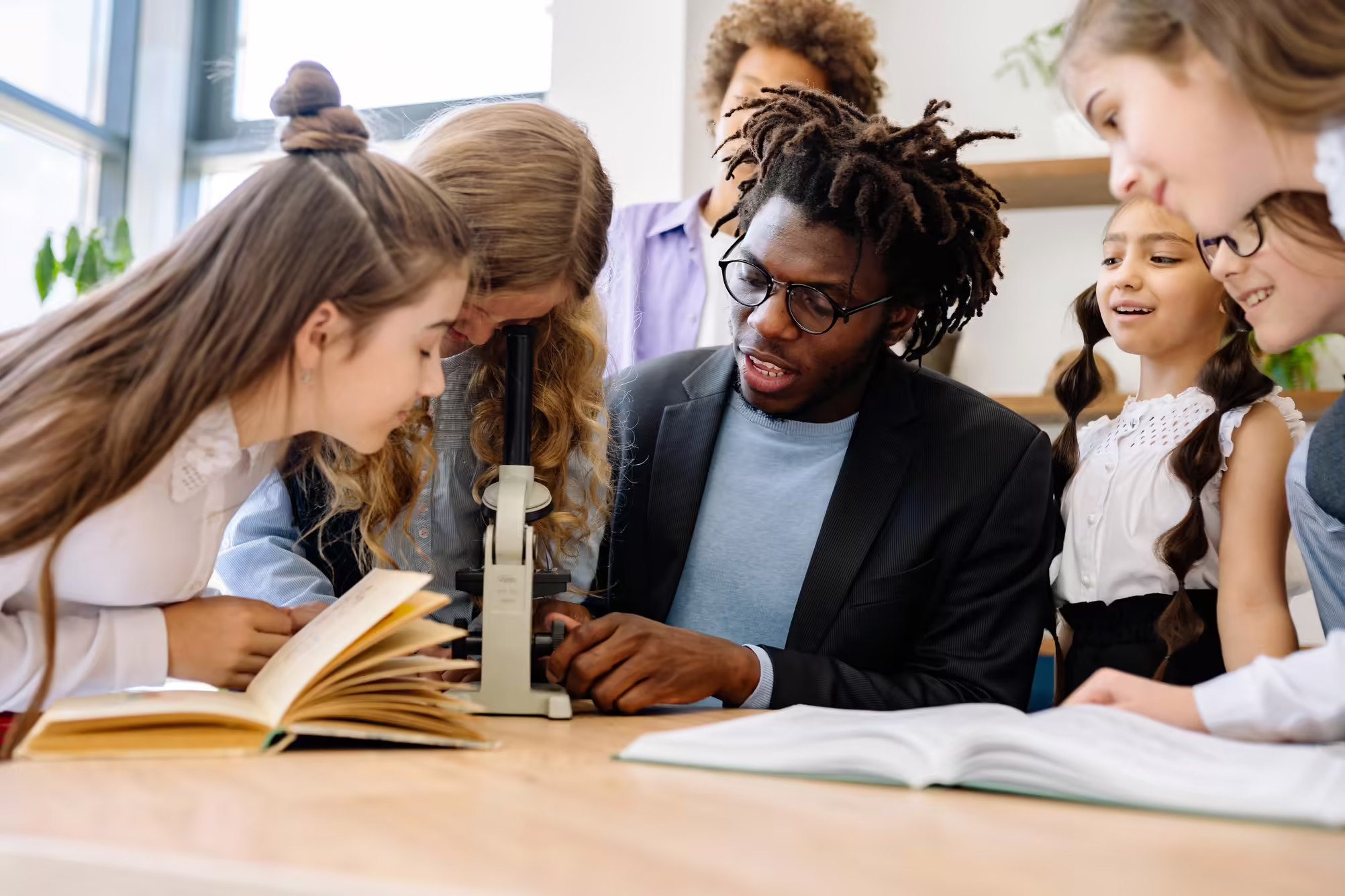 teacher with students around a microscope