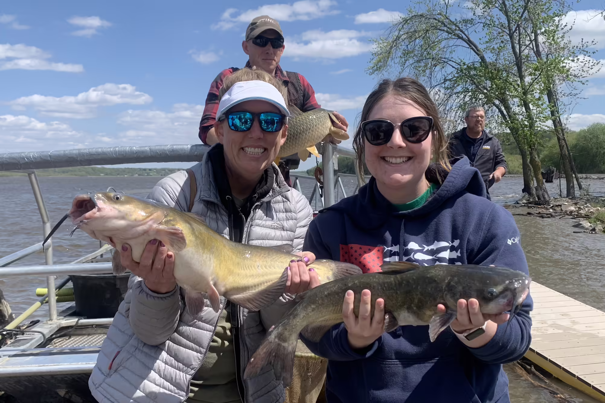 Two Master Naturalist each hold a large catfish 