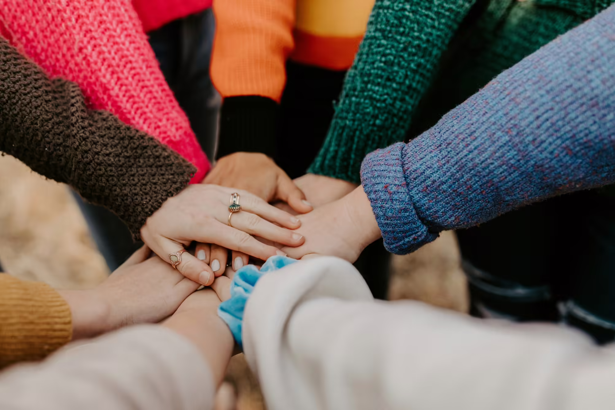 colorful sweaters where hands are coming together